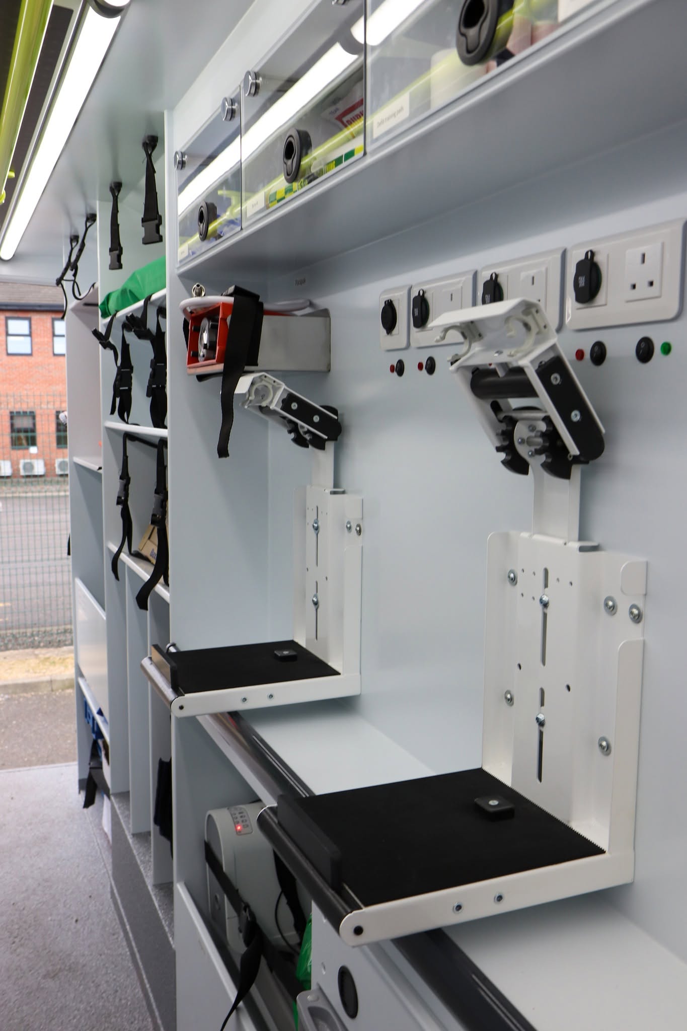 Wall-mounted equipment brackets and fold-down work surfaces inside a Medipro mobile education unit