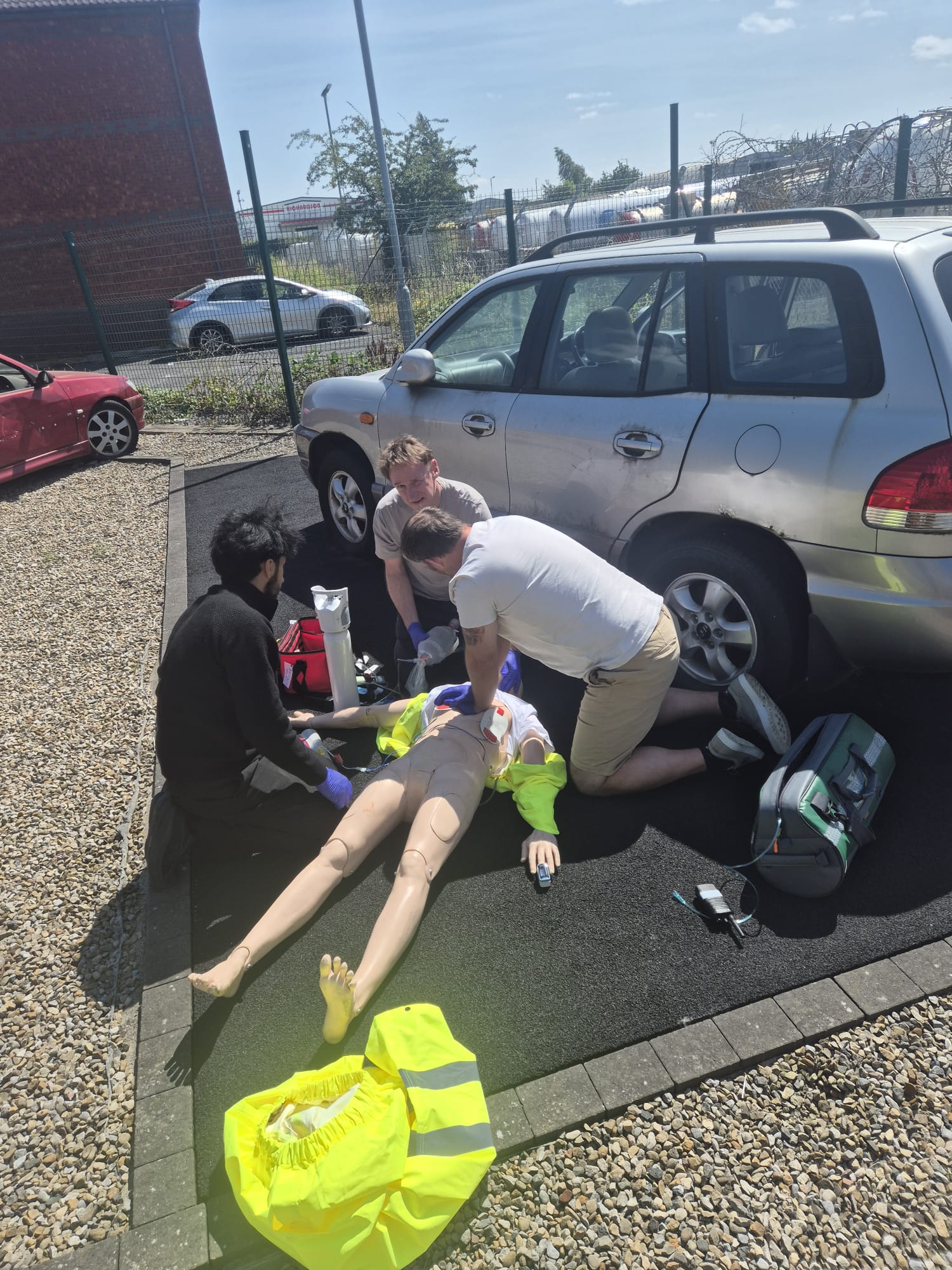 Learners treating a simulated roadside casualty beside a car